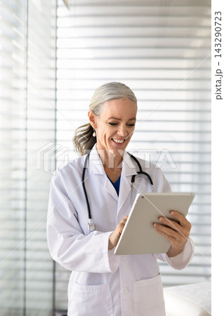 Smiling woman doctor checking digital tablet in clinic 143290723