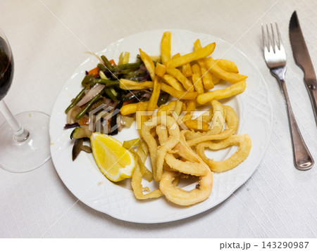 Deep-fried coated squid rings with fries and sauteed vegetables Deep-fried coated squid rings with fries and sauteed vegetables 143290987