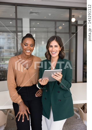 Confident businesswomen standing with digital tablet in office Confident businesswomen standing with digital tablet in office 143291112