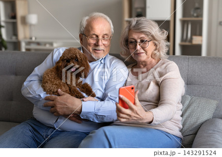 Senior couple video calling on smartphone with pet dog Senior couple video calling on smartphone with pet dog 143291524