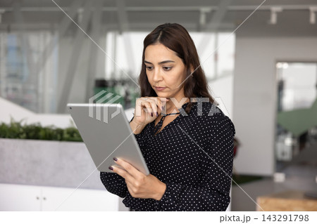 Focused businesswoman analyzing digital data on tablet Focused businesswoman analyzing digital data on tablet 143291798