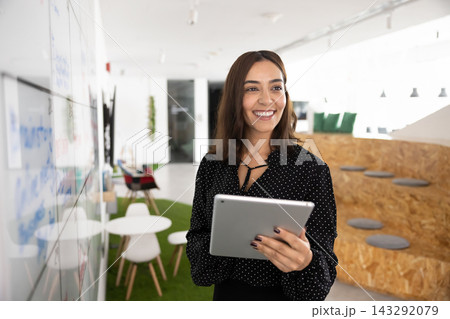 Smiling professional woman using tablet in coworking office Smiling professional woman using tablet in coworking office 143292079