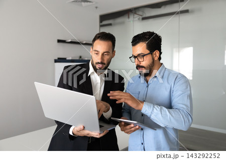 Multiethnic business colleagues working on digital project using laptop Multiethnic business colleagues working on digital project using laptop 143292252