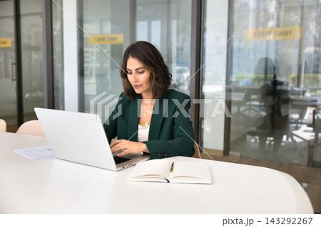 Focused businesswoman working on laptop in modern office Focused businesswoman working on laptop in modern office 143292267