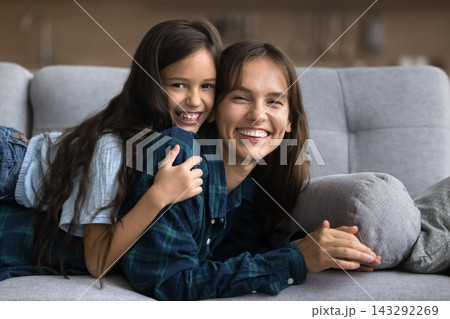 Mother and daughter lying on sofa looking at camera Mother and daughter lying on sofa looking at camera 143292269