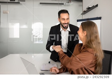 Happy multiethnic colleagues fist bumping in workplace Happy multiethnic colleagues fist bumping in workplace 143292309