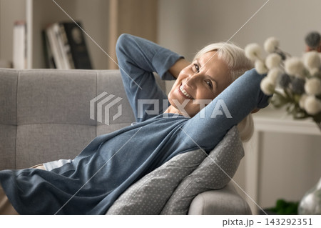 Serene aged woman lying on sofa with hands behind head Serene aged woman lying on sofa with hands behind head 143292351