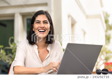 Cheerful young Hispanic remote worker woman sitting at workplace Cheerful young Hispanic remote worker woman sitting at workplace 143292710