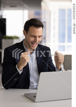 Hispanic entrepreneur celebrating business success by laptop at office desk Hispanic entrepreneur celebrating business success by laptop at office desk 143292819
