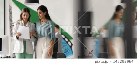 Confident female professional consulting colleague on paper document in office Confident female professional consulting colleague on paper document in office 143292964