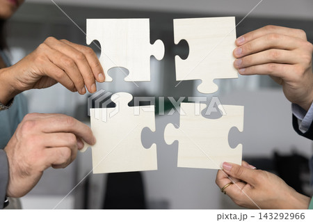Hands of diverse business partners join puzzle elements together 143292966