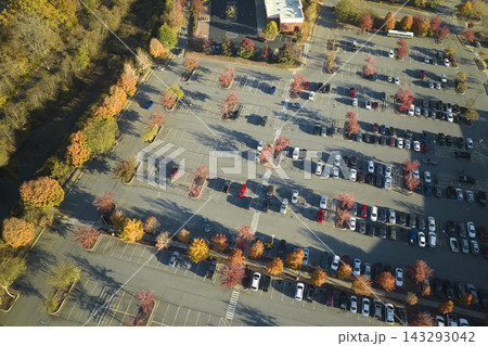 Aerial view of large parking lot with many parked colorful cars. Carpark at supercenter shopping mall with lines and markings for vehicle places and directions 143293042