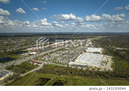 Aerial view of large parking lot in front of rgocery store with many parked colorful cars. Carpark at supercenter shopping mall with lines and markings for vehicle places and directions 143293044