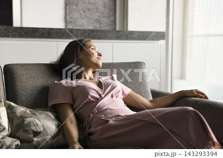 Calm relaxed young woman recline on sofa with serene smile Calm relaxed young woman recline on sofa with serene smile 143293394