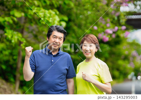 緑の中でガッツポーズで微笑むシニア夫婦 緑の中でガッツポーズで微笑むシニア夫婦 143295003