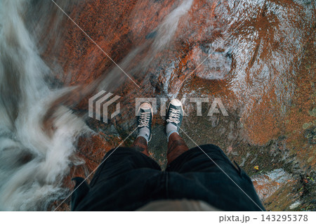 Top down view of a traveler standing on wet rocks near a fast flowing stream in the forest. Top down view of a traveler standing on wet rocks near a fast flowing stream in the forest. 143295378