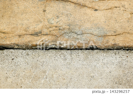 Close up of an old weathered concrete pavement with cracks and a deep joint dividing two slabs, showing raw texture and industrial grunge details. Textured background Close up of an old weathered concrete pavement with cracks and a deep joint dividing two slabs, showing raw texture and industrial grunge details. Textured background 143296257