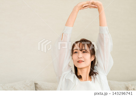 リビングで気持ちよくストレッチをする40代50代女性 リビングで気持ちよくストレッチをする40代50代女性 143296741