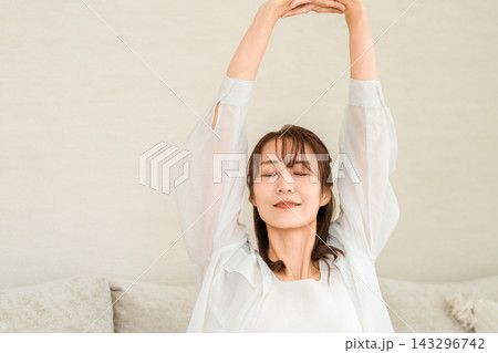 リビングで気持ちよくストレッチをする40代50代女性 リビングで気持ちよくストレッチをする40代50代女性 143296742