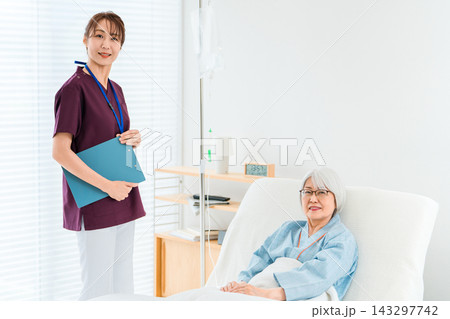 病院のベッドにいるシニア女性患者と看護師,介護士の女性スタッフ(医療イメージ) 病院のベッドにいるシニア女性患者と看護師,介護士の女性スタッフ(医療イメージ) 143297742