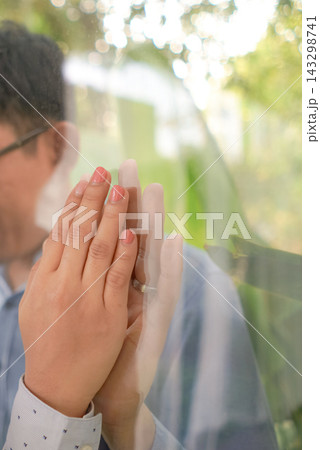 Two hands press against transparent glass surface in indoor space. Soft light and reflection create a quiet emotional mood. 143298741