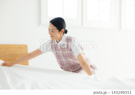 ベッドメイキングするエプロンの女性 ベッドメイキングするエプロンの女性 143299351