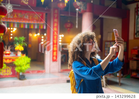 Caucasian Woman Travel Vlogger Taking Selfie at Colorful Chinese Temple with Red Lanterns and Decorations Caucasian Woman Travel Vlogger Taking Selfie at Colorful Chinese Temple with Red Lanterns and Decorations 143299628
