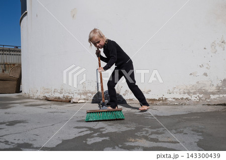 girl in black wetsuit sweeping wet concrete terrace with broom on sunny day girl in black wetsuit sweeping wet concrete terrace with broom on sunny day 143300439