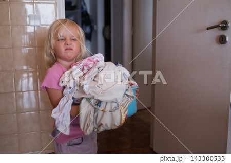 Girl Carrying a Basket of Laundry Near the Washing Machine Girl Carrying a Basket of Laundry Near the Washing Machine 143300533