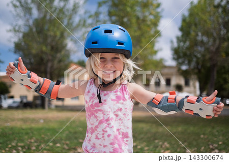 Cute Blonde Toddler in Safety Equipment Giving Thumbs Up Gesture Outdoors 143300674