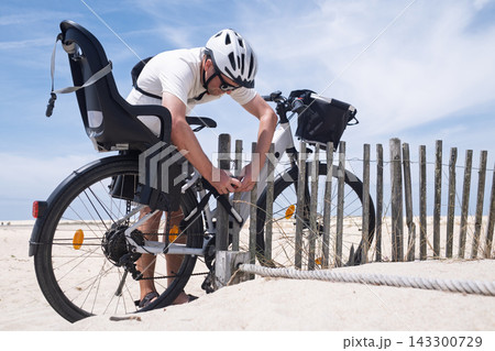 Cyclist Locking His Bicycle to a Metal Railing for Security Cyclist Locking His Bicycle to a Metal Railing for Security 143300729