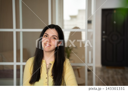 Smiling woman in yellow sleepwear sitting at home in a relaxed lifestyle portrait. Women's sleepwear everyday comfort self-confidence and home living Smiling woman in yellow sleepwear sitting at home in a relaxed lifestyle portrait. Women's sleepwear everyday comfort self-confidence and home living 143301331
