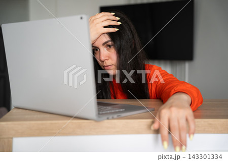 Tired woman resting her head while working on laptop at home desk. Remote work wellbeing screen break and digital fatigue awareness 143301334