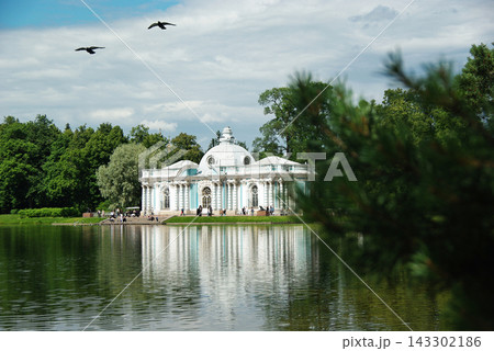 Classical Pavilion Reflected in Lake with Flying Birds in Historic Park 143302186