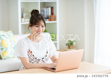 リビングでパソコンを使う若い女性 リビングでパソコンを使う若い女性 143302778