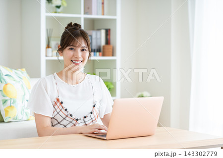 リビングでパソコンを使う若い女性 143302779