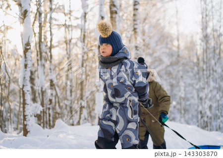 caucasian boys walking up the slope with snow tubing in forest on winter sunny day caucasian boys walking up the slope with snow tubing in forest on winter sunny day 143303870