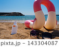 Sunscreen SPF50, sunglasses and swim ring are on the sand by the sea 143304087