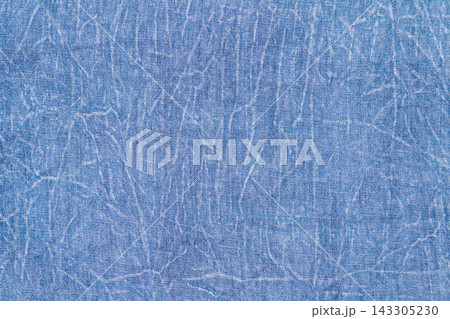 Blue denim fabric texture with creases and worn vintage jean background 143305230