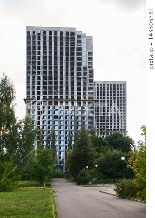 Under construction high rise building with crane above, concrete facade and window grid in urban park Under construction high rise building with crane above, concrete facade and window grid in urban park 143305581