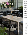 Outdoor cafe tables with woven rope chairs, potted hydrangeas on windowsill, marble tabletops on brick pavement, cozy urban terrace for restaurant or hospitality use Outdoor cafe tables with woven rope chairs, potted hydrangeas on windowsill, marble tabletops on brick pavement, cozy urban terrace for restaurant or hospitality use 143305672