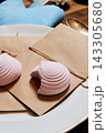 Pink macarons on kraft paper with twine, blue fabric napkin, white plate in warm kitchen lighting, sugar shells and delicate fillings visible, bakery dessert scene, pastel confectionery display Pink macarons on kraft paper with twine, blue fabric napkin, white plate in warm kitchen lighting, sugar shells and delicate fillings visible, bakery dessert scene, pastel confectionery display 143305680