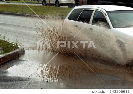 Splashes from a car driving on a road in the rain, uneven road surface Splashes from a car driving on a road in the rain, uneven road surface 143306611