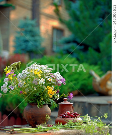 Clay pottery, cherries and wildflowers on a table in the courtyard of a country house. Clay pottery, cherries and wildflowers on a table in the courtyard of a country house. 143306615
