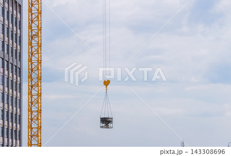 Tower crane lifting concrete hopper at high rise site, urban growth and real estate investment concept Tower crane lifting concrete hopper at high rise site, urban growth and real estate investment concept 143308696