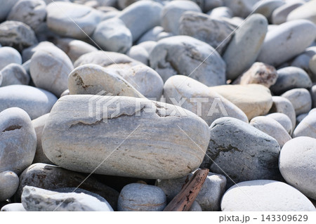 Close-up view of smooth, light grey river stones and pebbles lying on a natural beach. Close-up view of smooth, light grey river stones and pebbles lying on a natural beach. 143309629