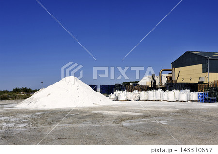 Industrial Salt Pile and Warehouse Storage Yard Under Blue Sky 143310657