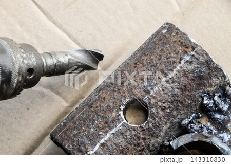 Drill Bit Cutting Rusty Metal Plate in Workshop Close-Up Drill Bit Cutting Rusty Metal Plate in Workshop Close-Up 143310830