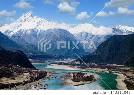 Majestic Snow Capped Mountains Overlooking a Turquoise River Valley in Tibet Majestic Snow Capped Mountains Overlooking a Turquoise River Valley in Tibet 143311042