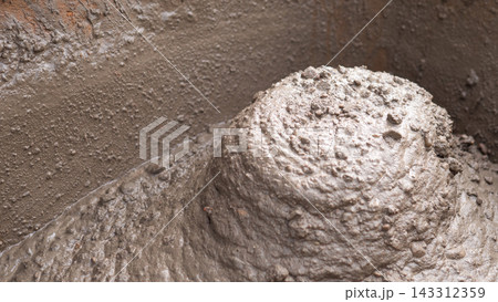 Wet mud and dense brown clay cling to uneven rough surface, forming layered gritty crust with glossy highlights. Soft light emphasizes mineral texture, tactile bumps. Wet mud and dense brown clay cling to uneven rough surface, forming layered gritty crust with glossy highlights. Soft light emphasizes mineral texture, tactile bumps. 143312359
